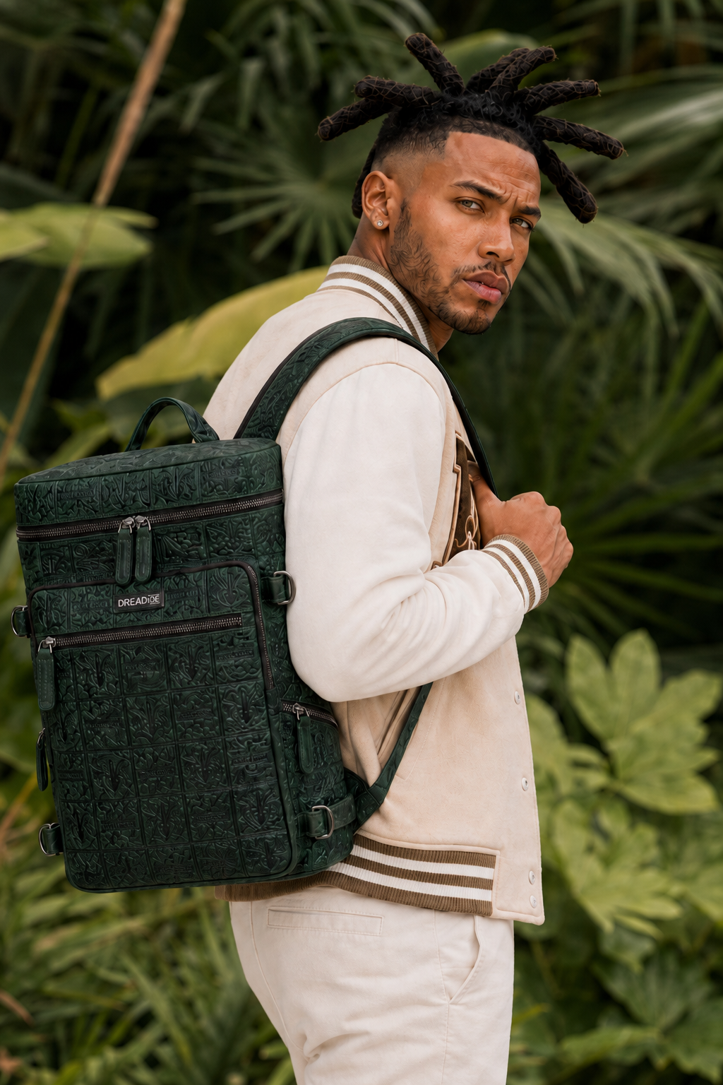 Model seated with the green DREAD IX backpack against a white studio background