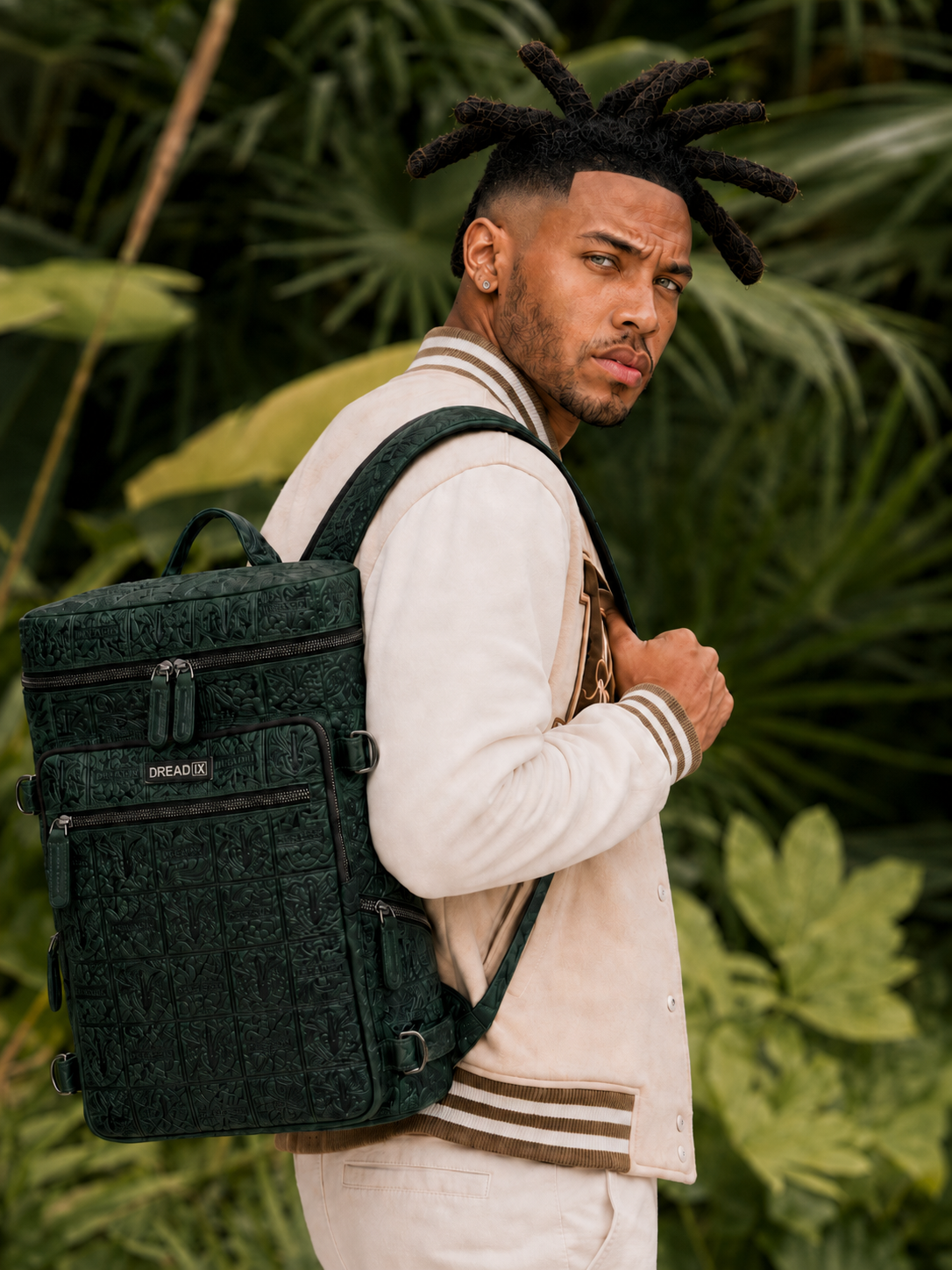 Model seated with the green DREAD IX backpack against a white studio background